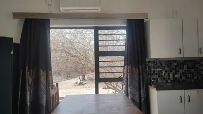 a kitchen with a large window with a view of a yard at Gemsbokrus in Marloth Park