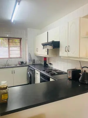 a kitchen with white cabinets and a black counter top at Charming Hideaway in Sandton