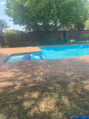a swimming pool in a yard next to a tree at Charming Hideaway in Sandton
