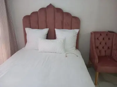 a bed with a red headboard and a chair at MamSwazi & Bitana Resorts n Restaurants in Pretoria