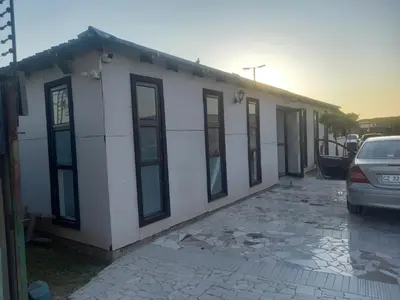 a white building with a car parked in front of it at MamSwazi & Bitana Resorts n Restaurants in Pretoria