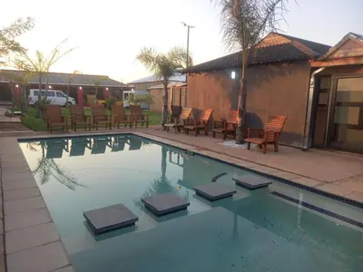 a swimming pool with chairs and chairs in a yard at MamSwazi & Bitana Resorts n Restaurants in Pretoria