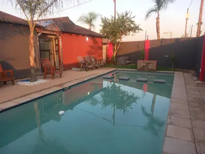 a swimming pool in a yard with a red building at MamSwazi & Bitana Resorts n Restaurants in Pretoria