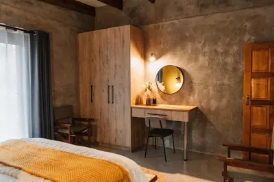 a bedroom with a bed and a desk and a mirror at Chawal Stays Ribbok in Marloth Park