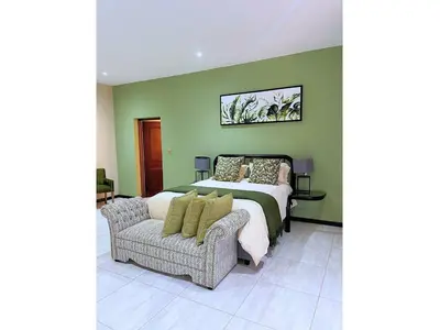 a bedroom with a bed and a couch and a chair at Mushavi Manor in Sybrandskraal
