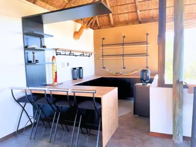 a kitchen with a wooden counter and stools at Mushavi Manor in Sybrandskraal