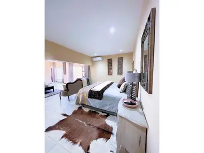 a bedroom with a bed and a desk and a couch at Mushavi Manor in Sybrandskraal