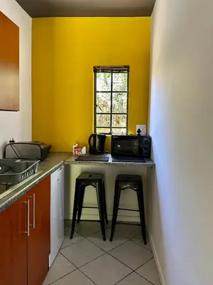 a kitchen with a counter with stools and a microwave at Pass-through Apartments in Pretoria