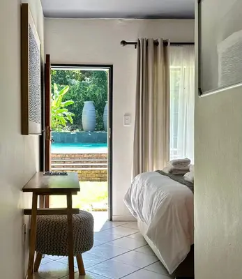 a bedroom with a bed and a table and a window at Pass-through Apartments in Pretoria