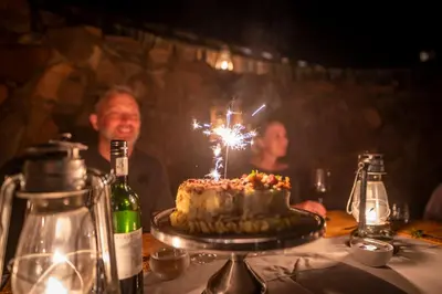 a man sitting at a table with a cake with a sparkler at Ekuthuleni Lodge in Welgevonden Game Reserve