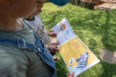 a woman holding up a book with a child at Ekuthuleni Lodge in Welgevonden Game Reserve