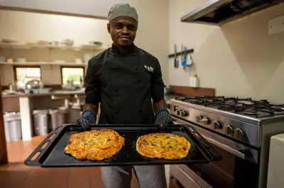 a man holding a tray with two pizzas on it at Ekuthuleni Lodge in Welgevonden Game Reserve