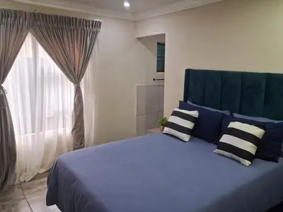 a bedroom with a blue bed with pillows and a window at Eazistay Motel - Letlhabile in Brits