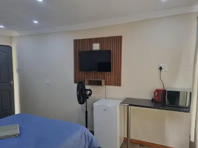 a room with a bed and a television on the wall at Eazistay Motel - Letlhabile in Brits