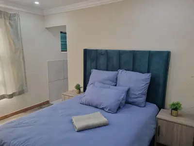 a bed with blue sheets and pillows in a room at Eazistay Motel - Letlhabile in Brits