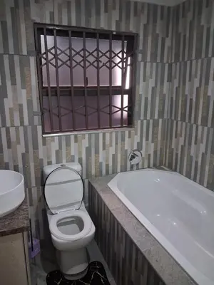 a bathroom with a toilet and a tub and a window at Eazistay Motel - Letlhabile in Brits
