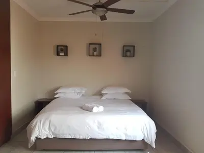 a bedroom with a white bed with a ceiling fan at Private Apartments & Biz Stays Pretoria in Pretoria