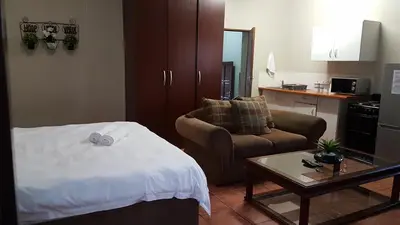 a room with a bed and a couch and a table at Private Apartments & Biz Stays Pretoria in Pretoria