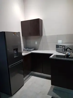 a kitchen with brown cabinets and a stainless steel refrigerator at Private Apartments & Biz Stays Pretoria in Pretoria