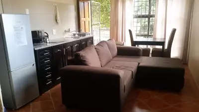 a living room with a couch and a kitchen at Private Apartments & Biz Stays Pretoria in Pretoria