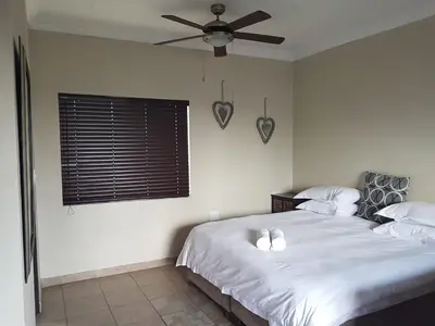 a bedroom with a bed with white sheets and a ceiling fan at Private Apartments & Biz Stays Pretoria in Pretoria