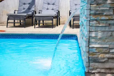 a swimming pool with chairs and a water hose at 118 Bayley Street in Benoni