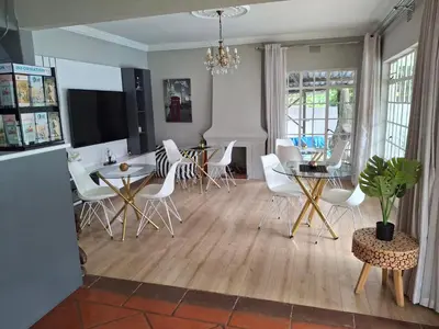 a kitchen and dining room with white chairs and a table at 118 Bayley Street in Benoni