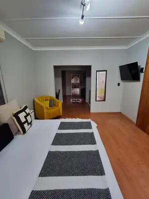 a living room with a bed and a yellow couch at 118 Bayley Street in Benoni