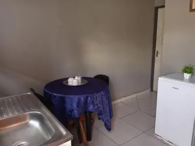 a small table with a purple table cloth in a kitchen at Matswabolle Guest Lodge in Gowe