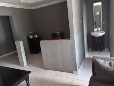 a bathroom with a sink and a couch and a mirror at Matswabolle Guest Lodge in Gowe