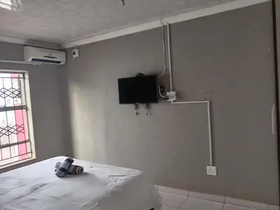 a bedroom with a bed and a tv on the wall at Matswabolle Guest Lodge in Gowe