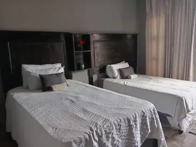 two beds sitting next to each other in a bedroom at Matswabolle Guest Lodge in Gowe