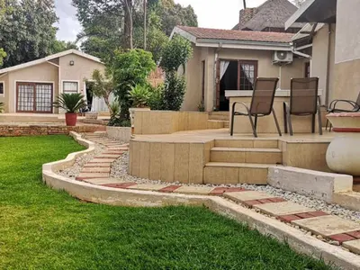 a backyard with a patio with two chairs and a house at Catwalk Lodge in Pretoria