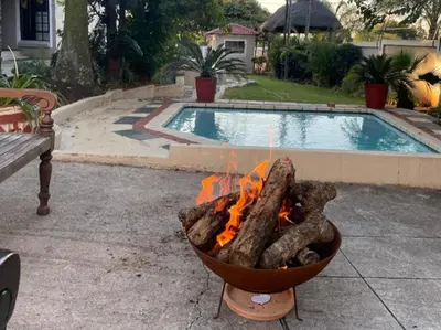 a fire pit in front of a swimming pool at Catwalk Lodge in Pretoria