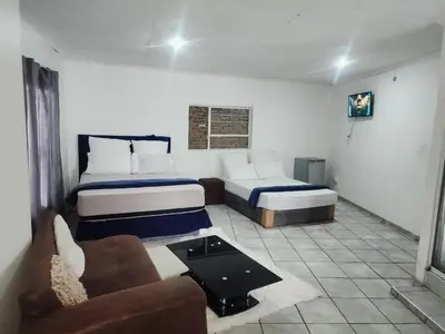 a hotel room with two beds and a couch at BATO Accommodation in Kempton Park