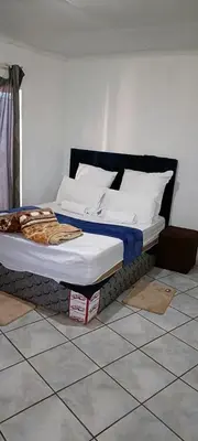 a bed sitting on a tiled floor in a room at BATO Accommodation in Kempton Park