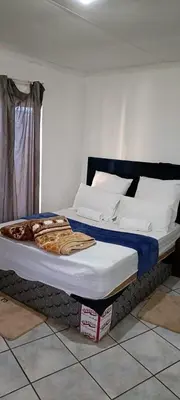 a bed with white pillows and a blue headboard at BATO Accommodation in Kempton Park