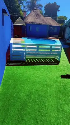 a yard with green grass and a blue building at BATO Accommodation in Kempton Park