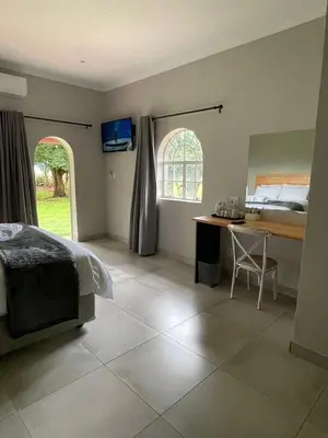 a bedroom with a bed and a desk and a table at Riecor Guest Farm in Thabazimbi