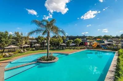 a swimming pool with a palm tree and a playground at Comfy 2-Bedroom at Kikuyu Estate in Johannesburg