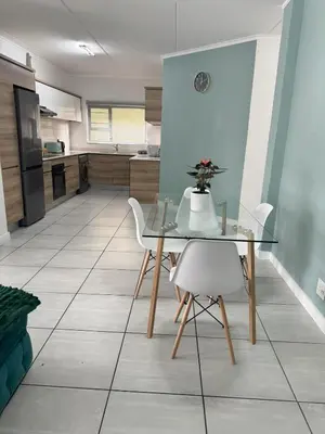 a kitchen with a glass table and white chairs at Comfy 2-Bedroom at Kikuyu Estate in Johannesburg