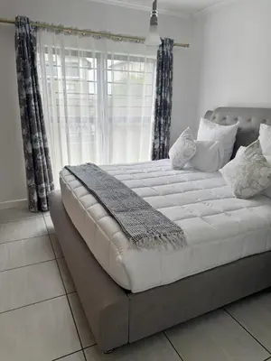 a large white bed in a room with a window at Comfy 2-Bedroom at Kikuyu Estate in Johannesburg