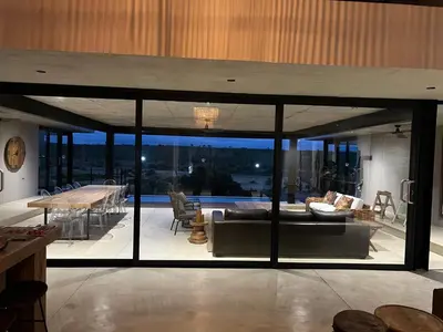 a living room with glass doors and a living room with a couch at Horizons River Lodge Mjejane in Hectorspruit