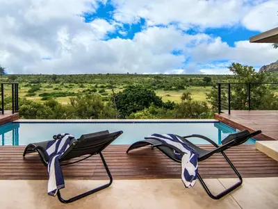 a pair of chairs sitting next to a swimming pool at Horizons River Lodge Mjejane in Hectorspruit