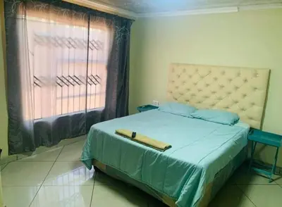 a bedroom with a bed with a blue blanket and a window at Musanda Lifestyle Centre in Makonde