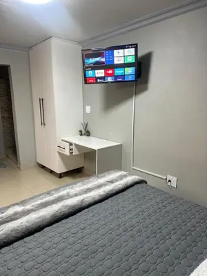 a bedroom with a bed and a television on the wall at Maduwa Guest House in Pretoria
