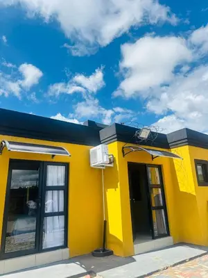 a yellow building with a blue roof at Maduwa Guest House in Pretoria