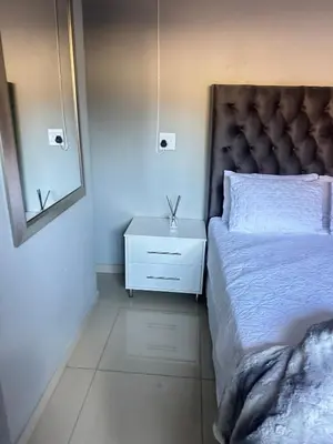 a bedroom with a bed and a nightstand and a mirror at Maduwa Guest House in Pretoria
