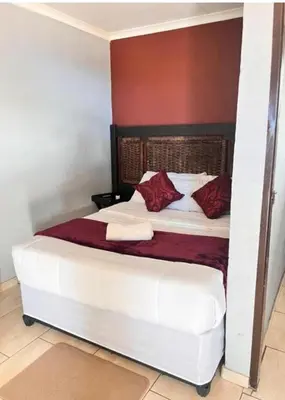 a bedroom with a white bed with red pillows at MD Guesthouse Debruin park in Ermelo