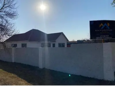 a white house behind a white fence with a sign at Begin Guesthouse in Ermelo